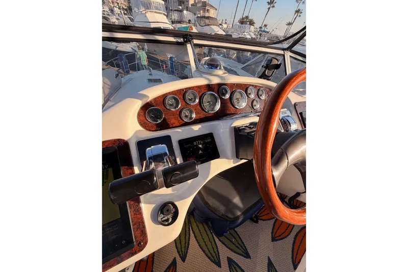 Slide: The Image of 1998 Sea Ray 420 Aft Cabin helm with gauges and wooden steering wheel. - 31