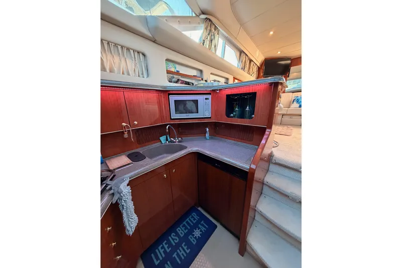 Slide: The Image of 1998 Sea Ray 420 Aft Cabin interior with kitchen, microwave, and cozy seating area. - 53