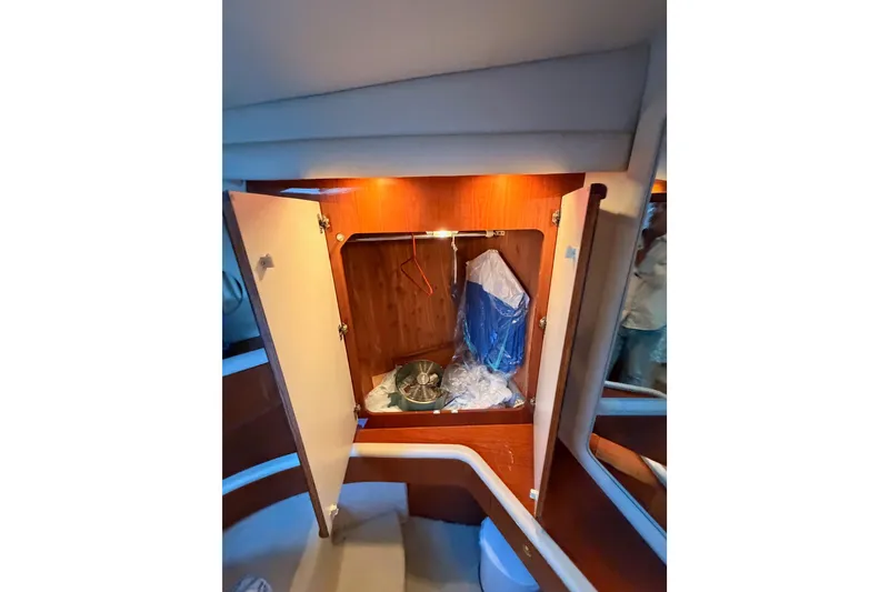 Slide: The Image of 1998 Sea Ray 420 Aft Cabin interior with open wooden cabinet and storage items. - 68