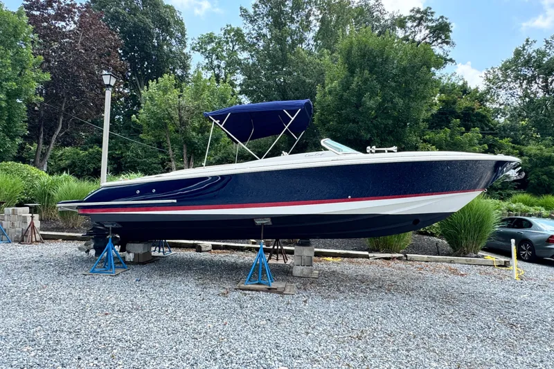 Slide: The Image of 2013 Chris-Craft Launch 28 boat on stands, surrounded by trees and gravel. - 0