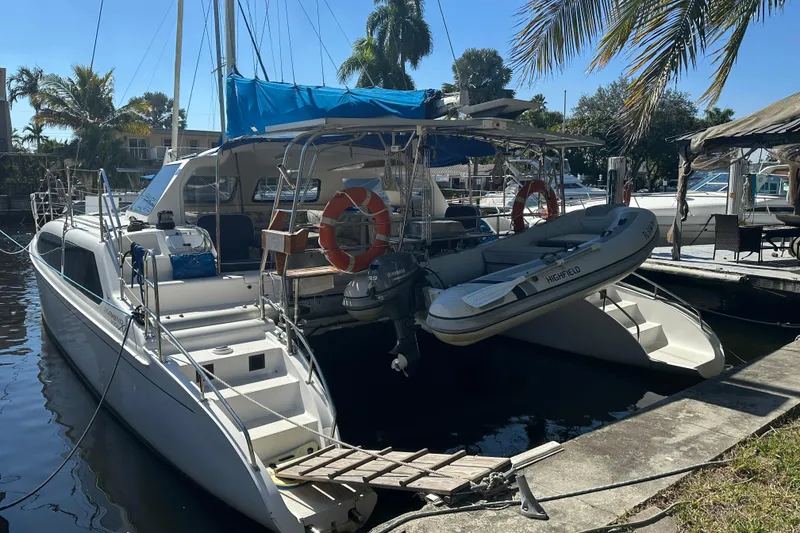Slide: The Image of 2008 Seawind 1000 XL catamaran docked with inflatable boat, surrounded by palm trees. - 59
