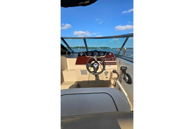 Slide: The Image of 2009 Sea Ray 270 Sundancer helm with steering wheel, dashboard, and lake view. - 11