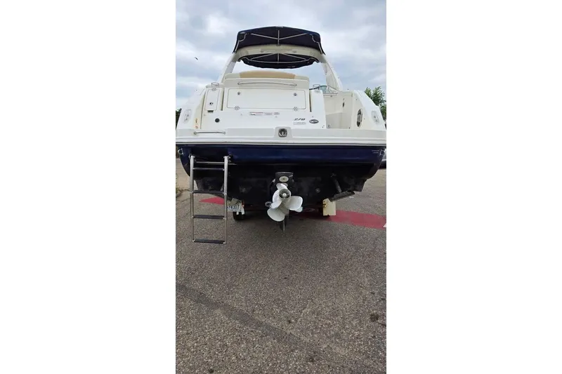 Slide: The Image of 2009 Sea Ray 270 Sundancer boat, rear view with ladder and propeller, parked on pavement. - 14