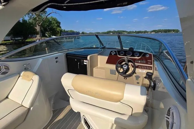 Slide: The Image of 2009 Sea Ray 270 Sundancer boat interior with steering wheel, beige seating, and lake view. - 18