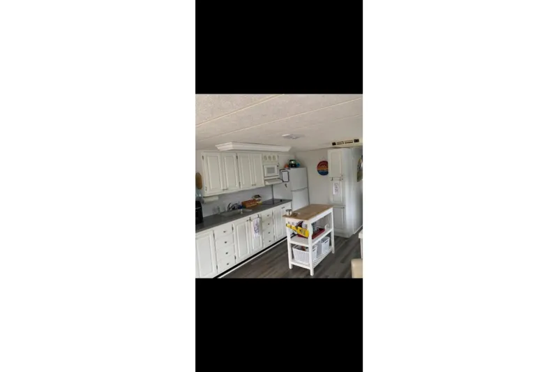 Slide: The Image of Interior of a 2000 Catamaran Cruisers 48, featuring a modern kitchen with white cabinetry. - 10
