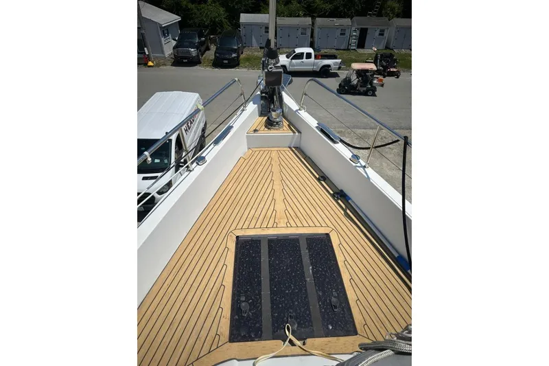 Slide: The Image of Deck view of 2019 Moody 54 DS yacht with wooden flooring and docked vehicles nearby. - 10