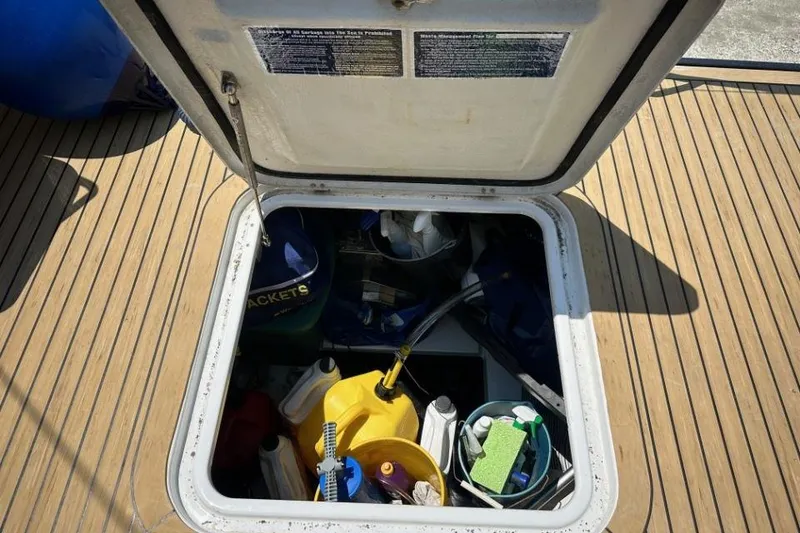 Slide: The Image of Open storage compartment on 2019 Moody 54 DS yacht deck, filled with cleaning supplies. - 23