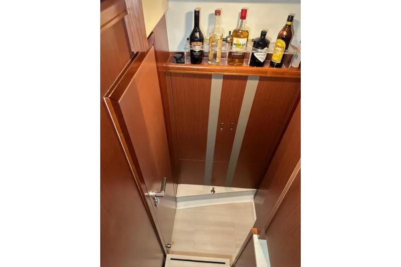Slide: The Image of Interior of 2019 Moody 54 DS yacht with wooden cabinetry and liquor bottles. - 46