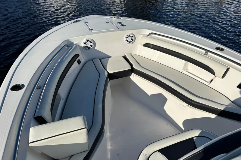 Slide: The Image of 2023 Tidewater 232 LXF boat interior with cushioned seating and speakers on water. - 10