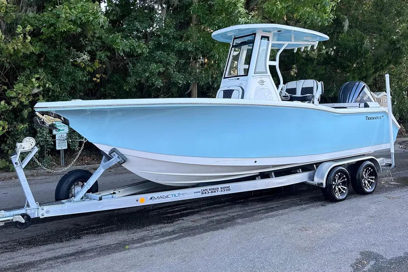 Slide: The Image of 2023 Tidewater 232 LXF boat on trailer, light blue hull, parked near trees. - 15