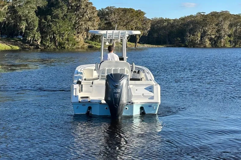 Slide: The Image of 2023 Tidewater 232 LXF boat cruising on a serene lake with lush greenery. - 4
