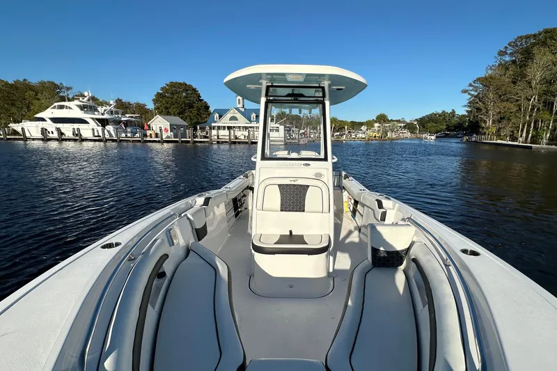 Slide: The Image of 2023 Tidewater 232 LXF boat on calm water, marina in background, clear blue sky. - 8