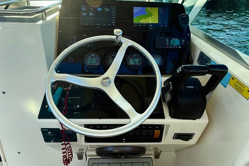 Slide: The Image of 2003 Pursuit 2870 Walkaround boat dashboard with steering wheel and navigation controls. - 15