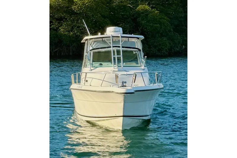 Slide: The Image of 2003 Pursuit 2870 Walkaround boat on water, front view, surrounded by greenery. - 4