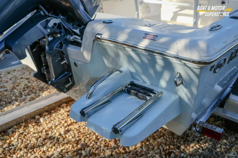 Slide: The Image of 2026 Key West 188 Bay Reef boat with motor and swim ladder, parked on gravel. - 19