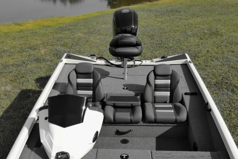 Slide: The Image of 2026 Ranger RT188 boat interior with seating and steering, parked on grassy shore. - 9