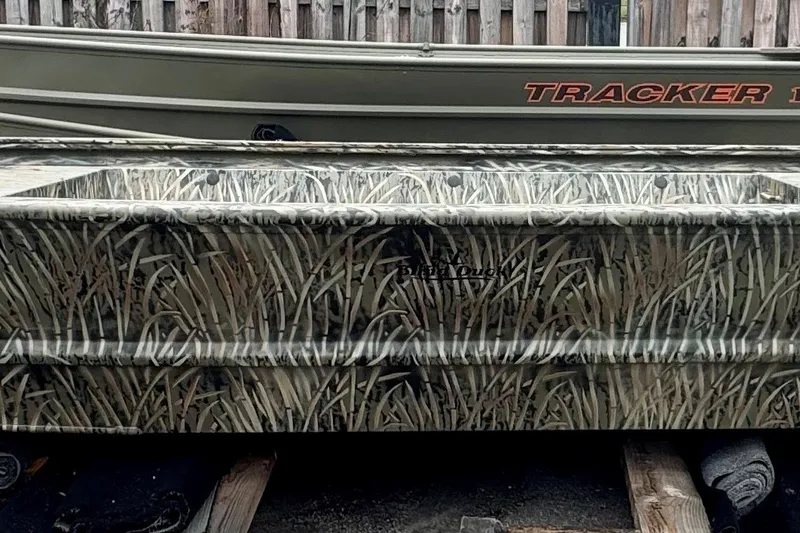 The Image of 2026 Tracker Grizzly 1648 Utility boat with camouflage design, parked outdoors. - 0