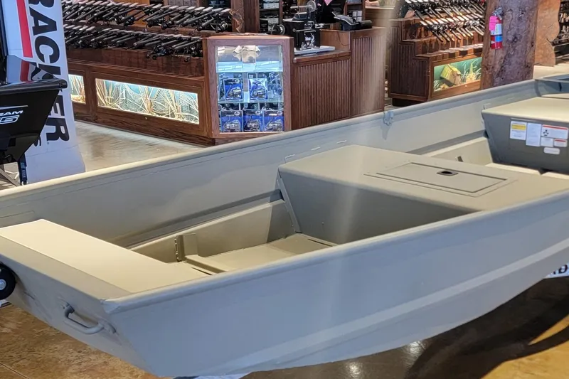 The Image of 2026 Tracker Grizzly 15 Jon boat displayed in a showroom with fishing gear. - 0