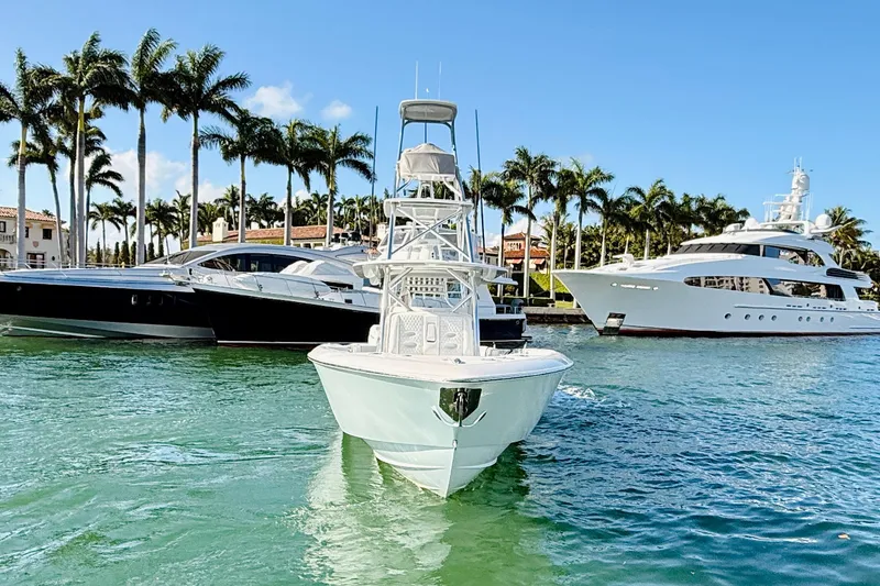 Slide: The Image of 2024 Contender 44 ST boat docked near luxury yachts and palm trees. - 24