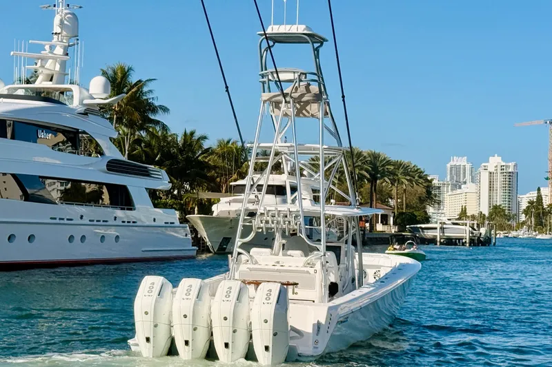 Slide: The Image of 2024 Contender 44 ST boat with quad engines cruising in a marina, surrounded by yachts and palm trees. - 29