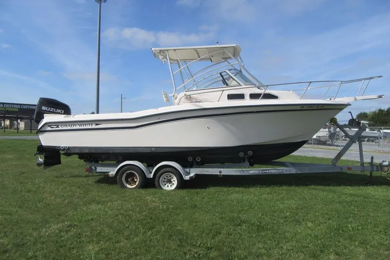 Slide: The Image of 1996 Grady-White Voyager 248 boat on trailer, grassy area, clear sky background. - 4