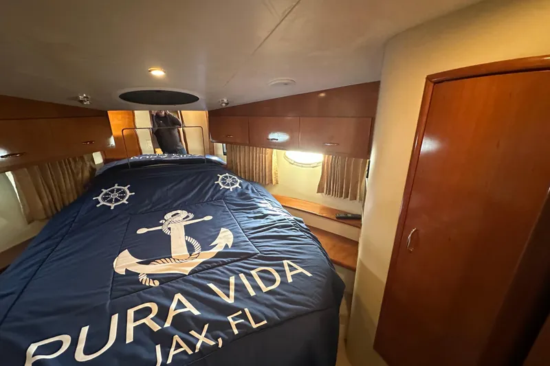 Slide: The Image of Interior of 2005 Carver 36 Super Sport with nautical-themed bedding, wooden cabinets, and porthole window. - 40