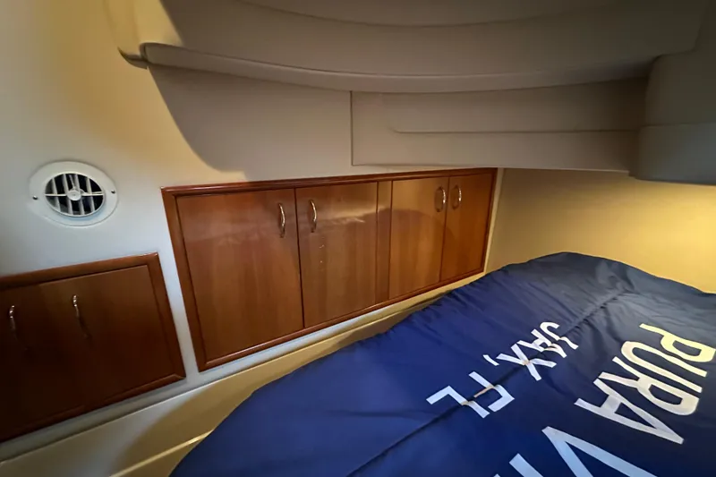 Slide: The Image of Interior cabin of 2005 Carver 36 Super Sport with wooden cabinets and blue bedding. - 48
