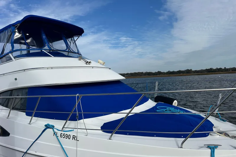 Slide: The Image of 2005 Carver 36 Super Sport yacht with blue covers docked on a calm waterway. - 8