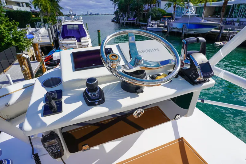 Slide: The Image of 2024 Invincible 43 Open Fisherman helm with Garmin navigation, docked by waterfront homes. - 49