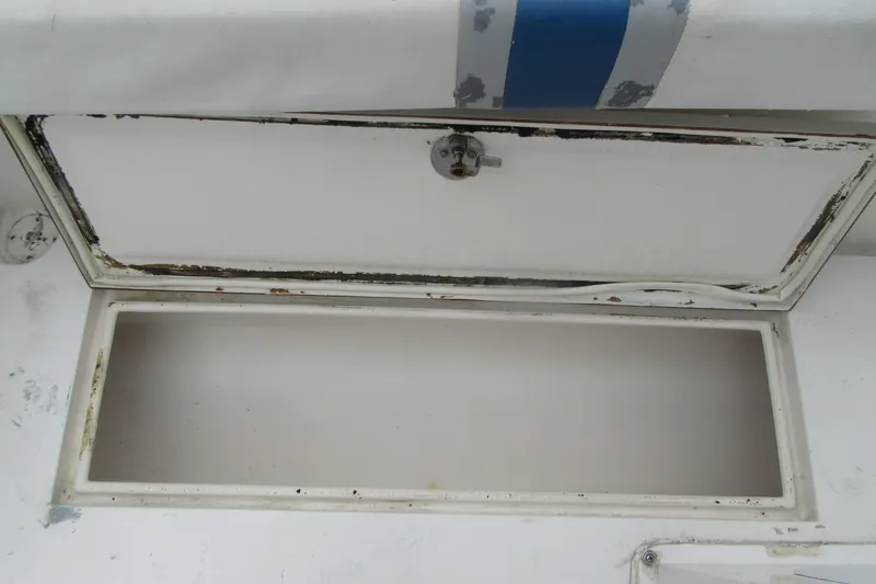 Slide: The Image of Open storage compartment on a 2005 Contender 23 CC boat, showing wear and rust. - 28