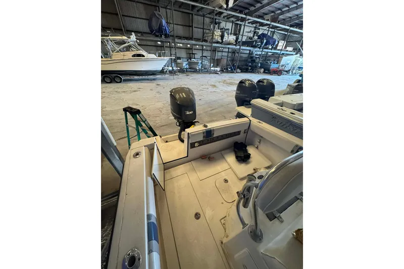 Slide: The Image of 2005 Contender 23 CC boat in storage, featuring outboard motor and spacious deck. - 7