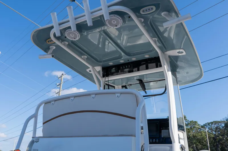 Slide: The Image of 2021 Sea Hunt Ultra 265 SE boat console with T-top under clear blue sky. - 18