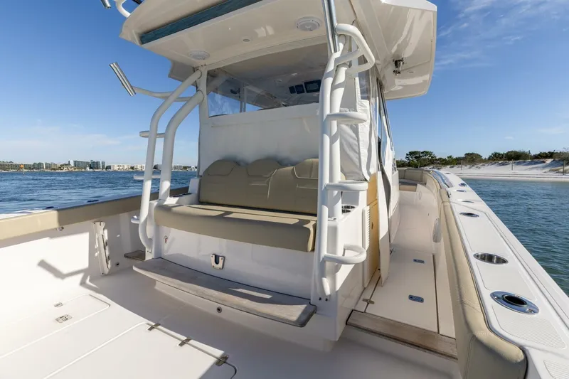 Slide: The Image of 2019 Pursuit S 368 Sport boat interior with seating, docked near a sandy beach. - 13