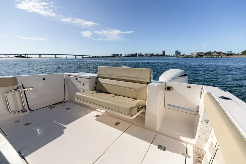 Slide: The Image of 2019 Pursuit S 368 Sport boat interior with seating, overlooking a scenic waterfront. - 23