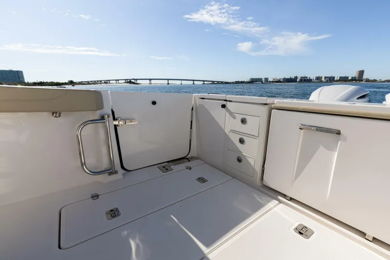 Slide: The Image of 2019 Pursuit S 368 Sport boat interior with storage, overlooking a scenic waterfront and bridge. - 26