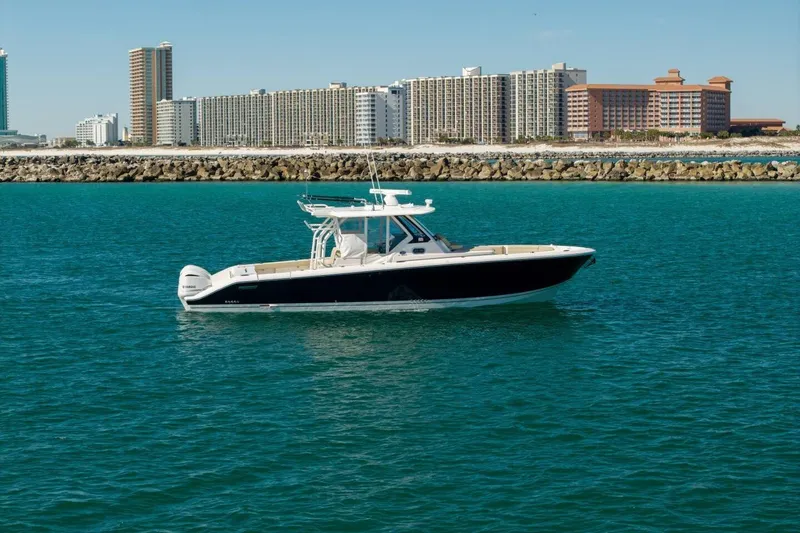 Slide: The Image of 2019 Pursuit S 368 Sport boat cruising near coastal city skyline. - 34