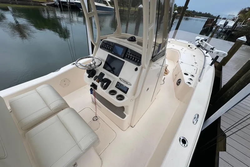 Slide: The Image of 2022 Grady-White 251 Coastal Explorer boat interior with helm and seating, docked by the water. - 22