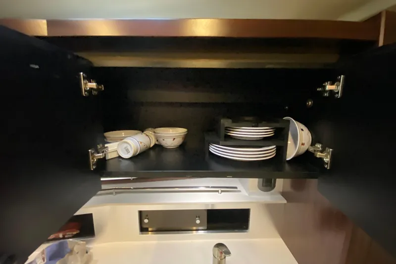 Slide: The Image of Open cabinet with dishes inside a 2017 Monterey 355 Sport Yacht kitchen. - 38