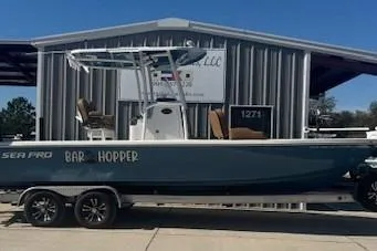 The Image of 2022 Sea Pro 248 Bay boat on trailer, parked outside a metal building. - 1