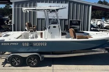 Slide: The Image of 2022 Sea Pro 248 Bay boat on trailer, labeled "Bar Hopper," parked outside a building. - 3