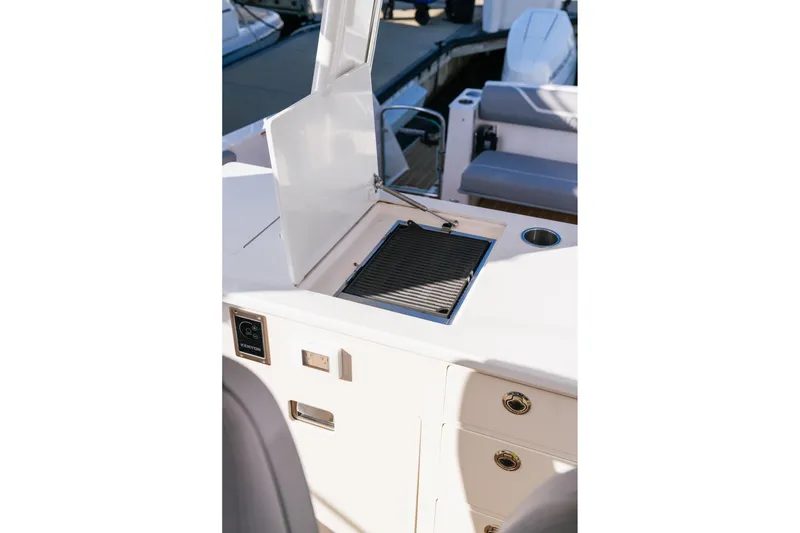 Slide: The Image of 2025 Regal 38 SAV boat grill station with open lid and storage drawers. - 14