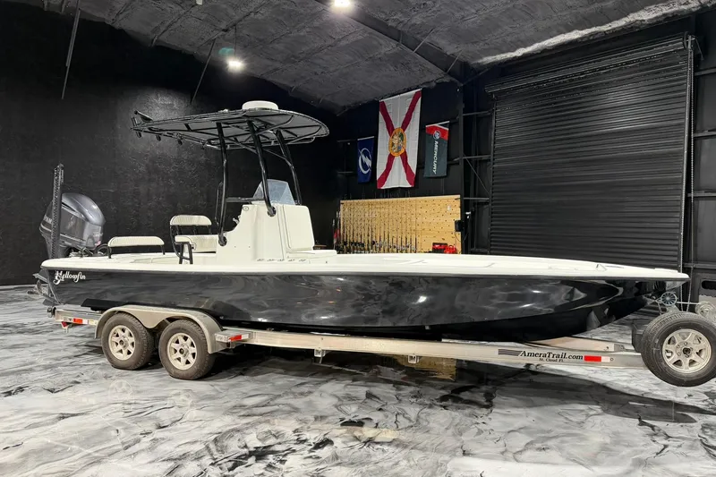 Slide: The Image of 2011 Yellowfin 24 Bay boat on trailer in indoor storage with flags. - 11