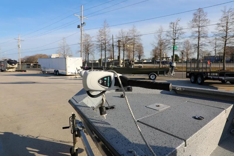 Slide: The Image of 2019 Express 18 boat with trolling motor in a parking lot, trailers in background. - 7