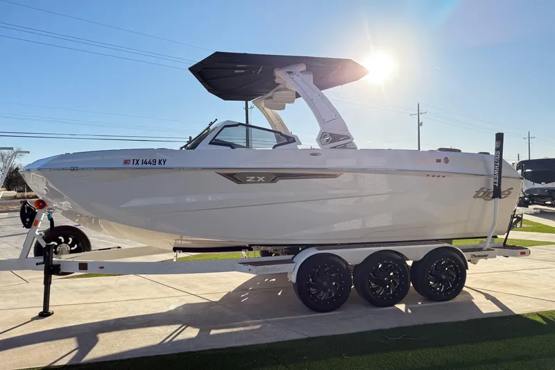 Slide: The Image of 2024 Tigé Ultré 23ZX boat on trailer, sunlit, sleek design, parked outdoors. - 3