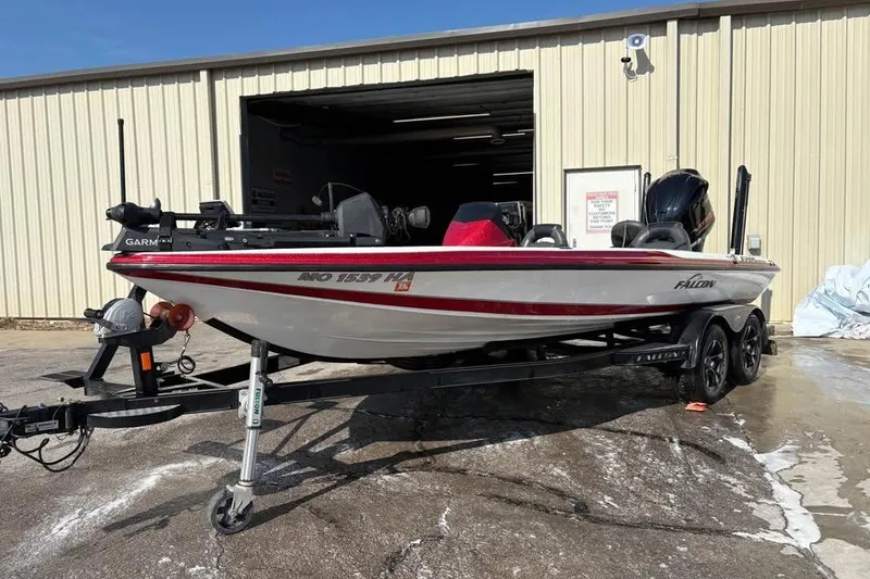 Slide: The Image of 2021 Falcon Boats F205 on trailer outside a garage, featuring red and white design. - 3