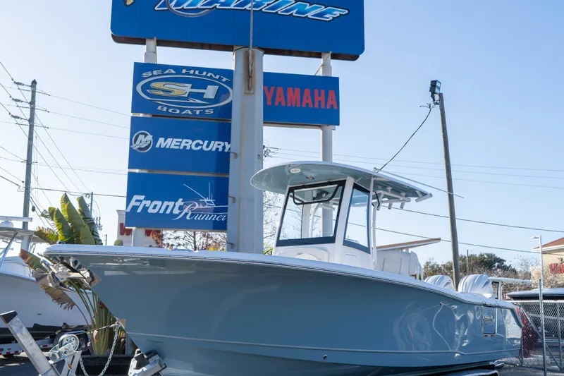 Slide: The Image of 2026 Sea Hunt Ultra 265 SE boat displayed at a dealership with marine brand signs. - 25
