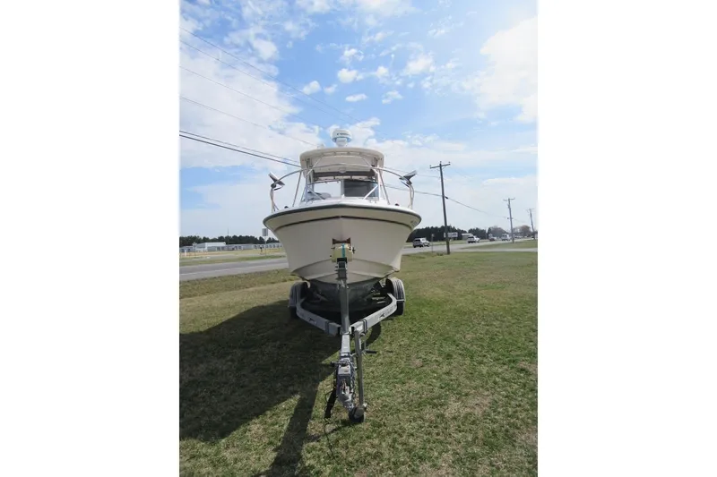 Slide: The Image of 2004 Grady-White Seafarer 228 boat on trailer, parked on grass under blue sky. - 10