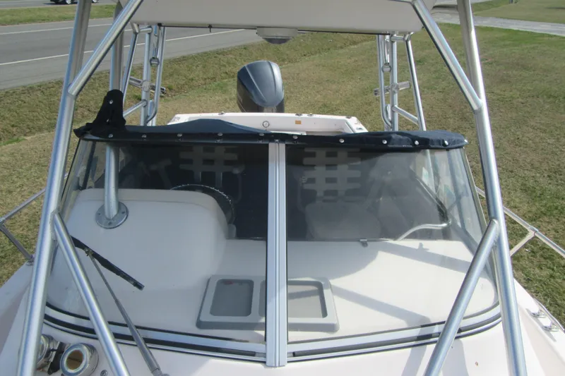 Slide: The Image of 2004 Grady-White Seafarer 228 boat with windshield and metal frame, parked on grass. - 22