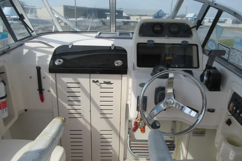 Slide: The Image of 2004 Grady-White Seafarer 228 boat cockpit with steering wheel and control panel. - 25