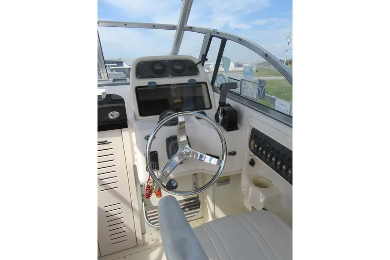 Slide: The Image of 2004 Grady-White Seafarer 228 boat helm with steering wheel and control panel. - 28